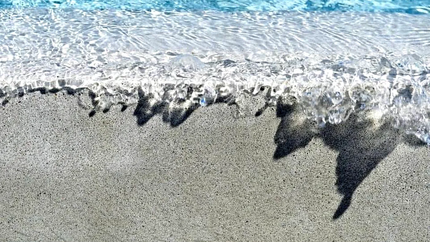 Water over the beach entry of a quartz aggregate pool